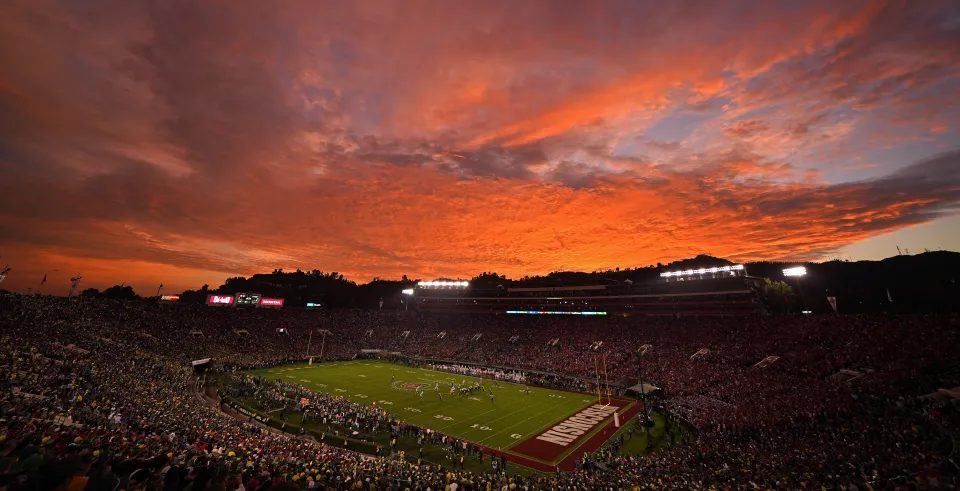 A packed bowl stadium under a burning orange sunset