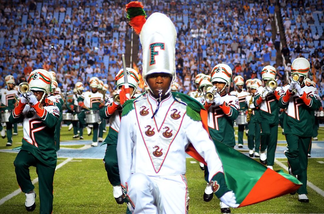 Drum major leading a marching band onto the field