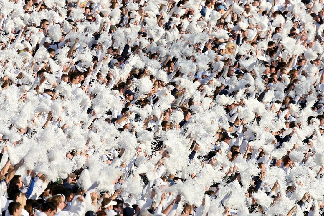 A white-out student section waving pom-poms